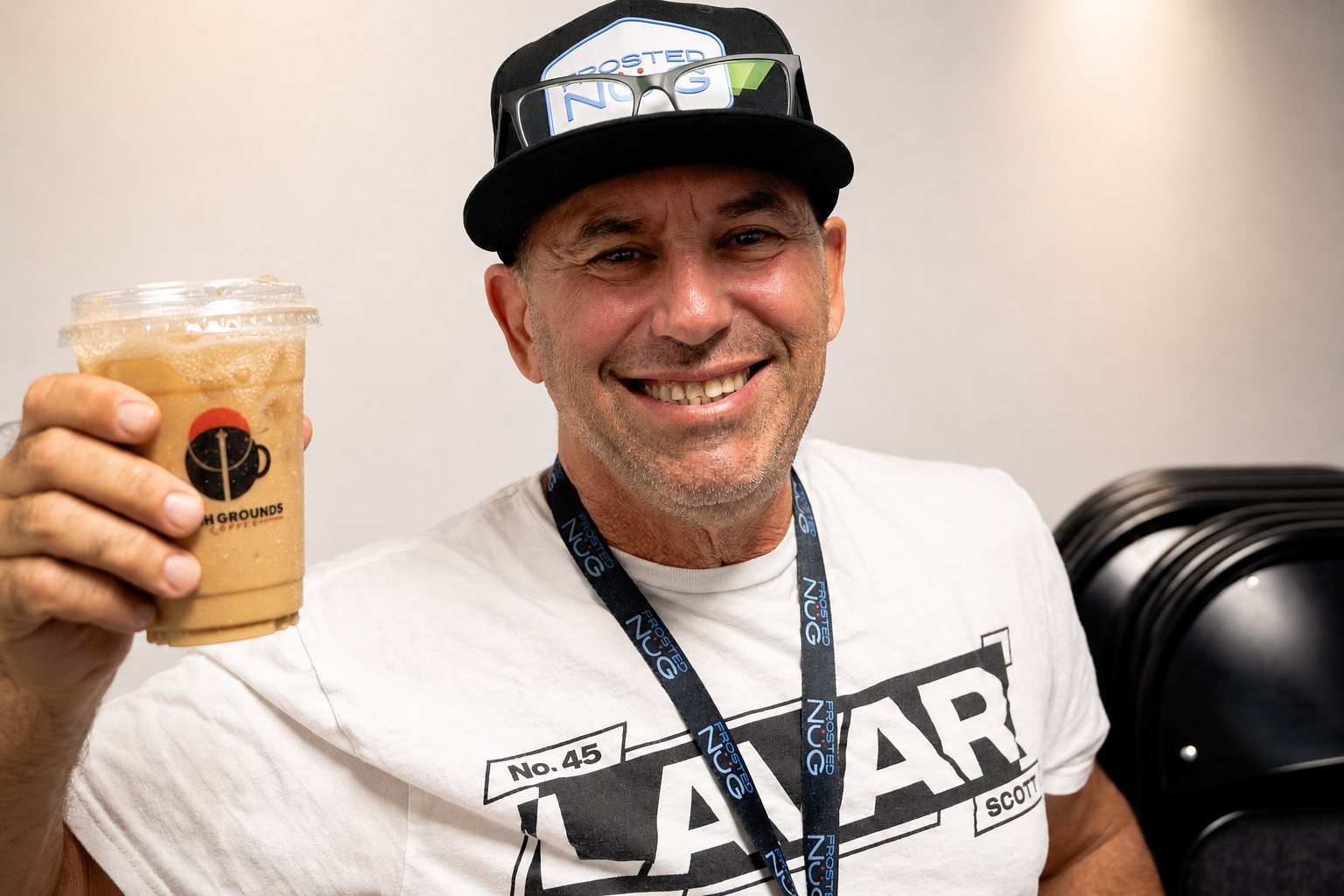 Smiling guest holding a High Grounds iced coffee
